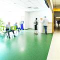 Stock Photo - View of the registration desk waiting area and a corridor in modern hospital with blurred figures of patients with a copy space.