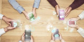 Stockfoto - Draufsicht auf Geschäftsleute bei Treffen über soziale Medien auf Smartphones auf hölzerner Tischplatte