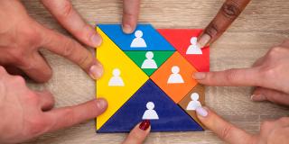 Gruppe von Menschen Hand auf bunten Tangram Puzzle Blöcke